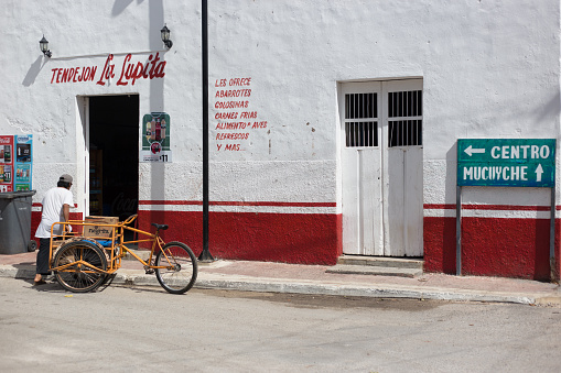 Abala, Yucatan, Mexico: A delivery man with a pedicab walks into a vibrant red and white shop in Abala, an indigenous village about 50 kilometers south of Merida, Mexico.