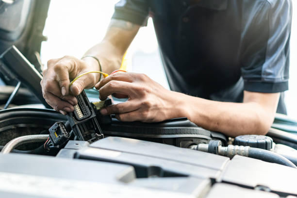 People or mechanic car repair during investigate cause of problem (electric system check) or working on automobile gasoline or diesel engine at garage stock photo