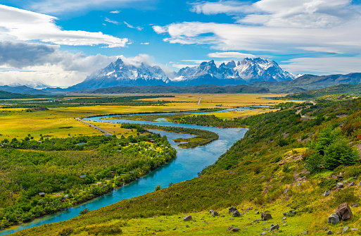 The Andes peaks of Paine Grande, Cuernos del Paine and Torres del Paine on a summer day with the turquoise glacier waters of the Serrano river in the foreground near Puerto Natales, Patagonia, Chile.