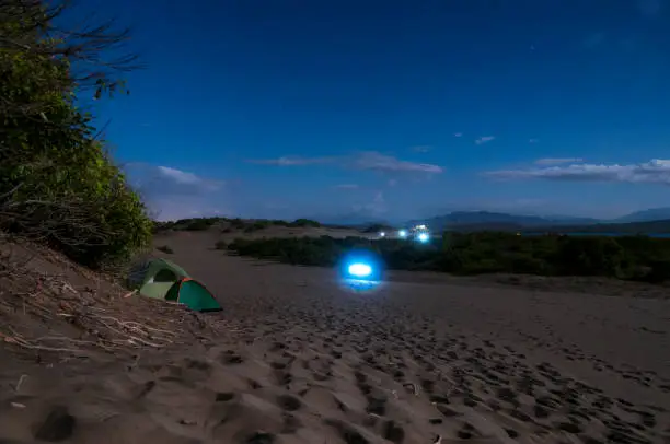 Descriptive scene of the night sky with the Milky Way during the eclipse of the moon on January 21, 2019, where the Orion, Pleiades, Can Major and thousands of stars in very dark skies are clearly seen on the sand dunes of Bani in the Dominican Republic. A blue tent enhances the interest of the composition where all the elements draw attention to venturing into adventure tourism