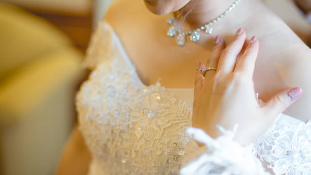 The bride in a white dress and her hand with a wedding ring wearing on her finger. stock photo