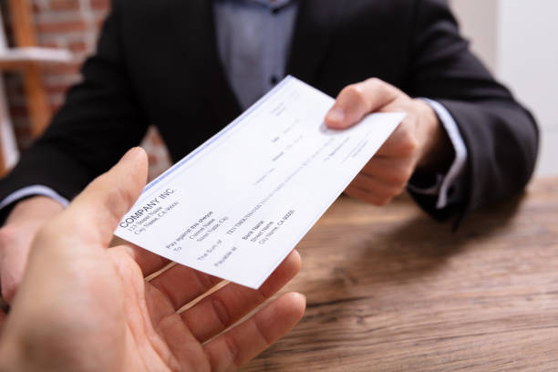 Man's Hands Giving Cheque To Other Person Close-up Of Businessman's Hands Giving Cheque To Other Person In Office paycheck photos stock pictures, royalty-free photos & images