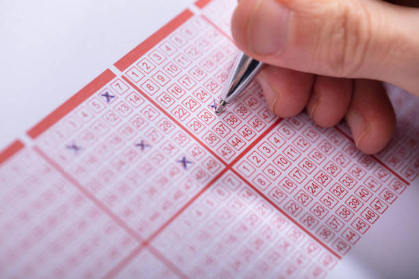 istock Person Marking Number On Lottery Ticket With Pen 1130220073