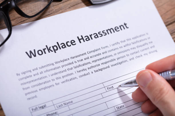 Man Filling Workplace Harassment Form Close-up Of A Man's Hand Filling Workplace Harassment Form harassment stock pictures, royalty-free photos & images