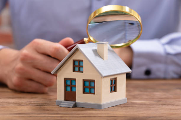 istock Businessman Holding Magnifying Glass Over House Model 1130220121
