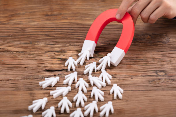 istock Hand Holding Red Horseshoe Magnet Attracting Human Figures 1130220123