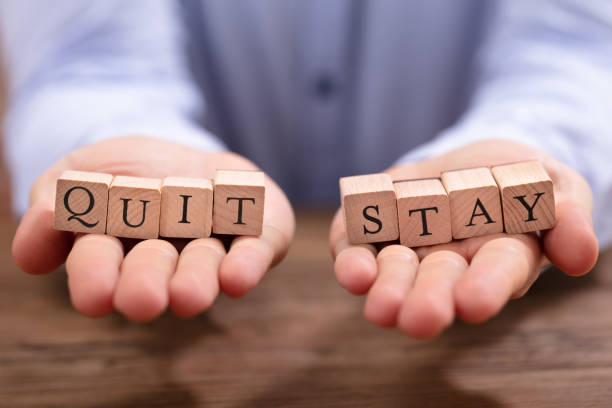 istock Businessperson Holding Quit And Stay Blocks 1130220139