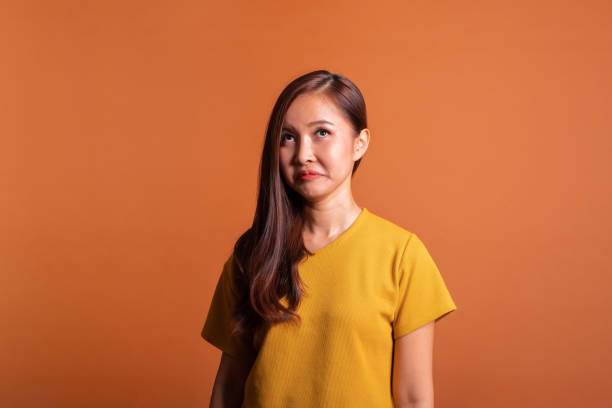 istock Young Asian woman face expression envy, jealous over orange background, studio shot 1130221147