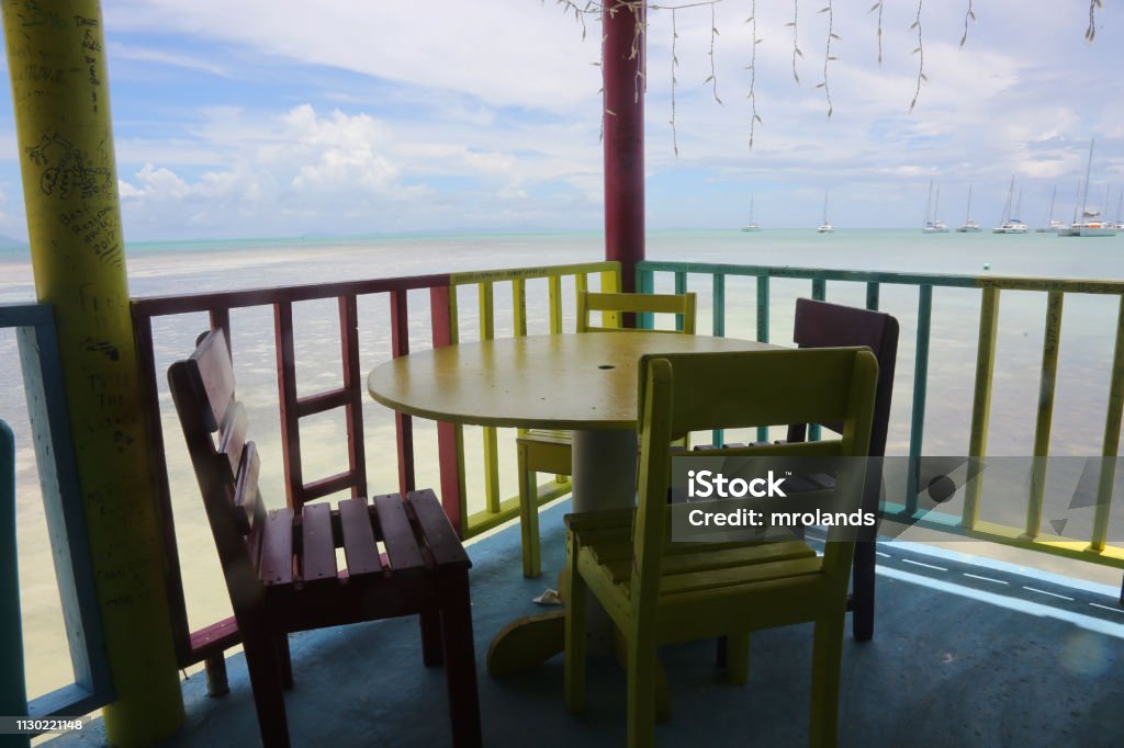 Colorful furniture on a deck built over the water Colorfully painted furniture sits on a equally colorful deck extending over the water on the island of Anegada in the British Virgin Islands. Anegada Stock Photo