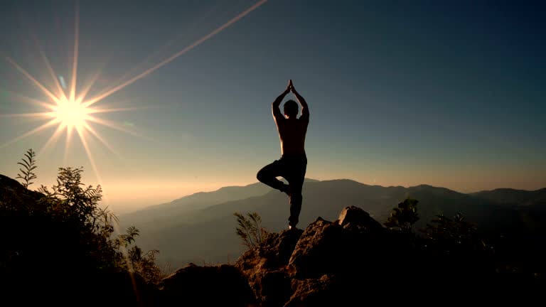 4K Man in meditation-Yoga position on the top of mountain at sunrise.