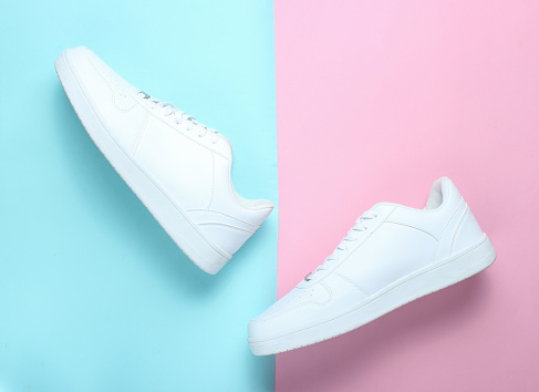 Fashionable white sneakers on a colored pastel background, minimalism, top view, creative layout, step