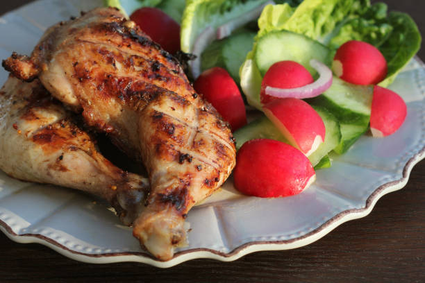 istock Grilled chicken quarters with salad for garnish on dark background. 1130233842