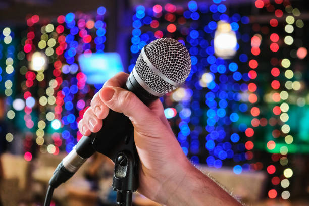 istock Microphone in man hands close-up on an abstract bokeh background. Blurred background with lights 1130234677