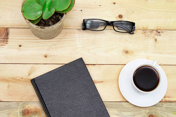 closed books with coffee cup, stamp and glasses on wooden table