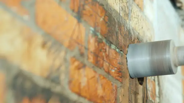 A diamond-tipped drill drills a hole in a brick wall