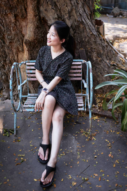 istock Asian girl sitting on rusty metal chair under tree 1130240548