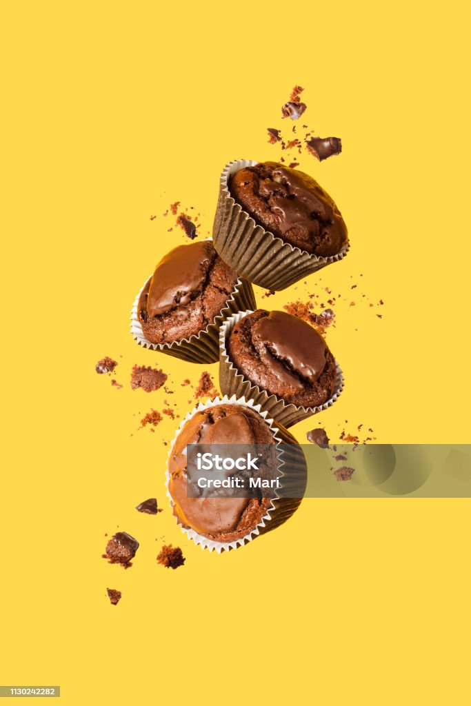 Flying chocolate cupcakes or cookies on yellow background. Mock up. Background concept. Food Stock Photo
