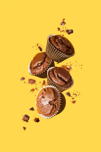 Photo of Flying chocolate cupcakes or cookies on yellow background. Mock up. Background concept.