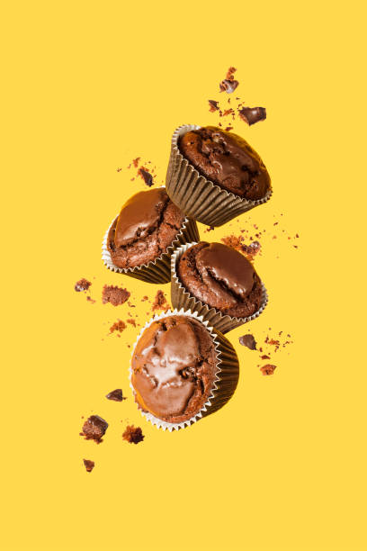 flying chocolate cupcakes or cookies on yellow background. mock up. background concept. - vertical drop imagens e fotografias de stock