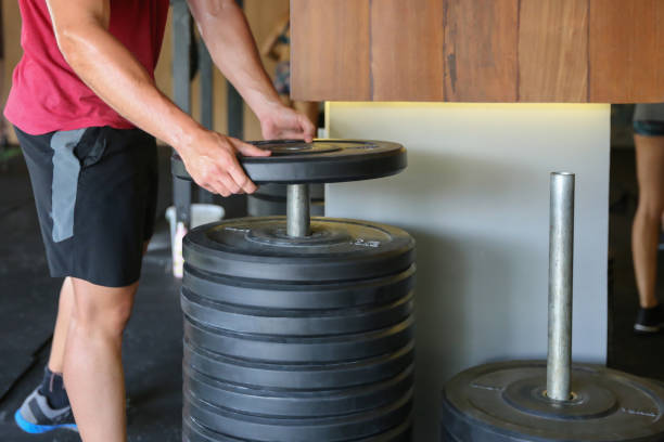 Close up shot of young men picking up weight plates for strength exercise