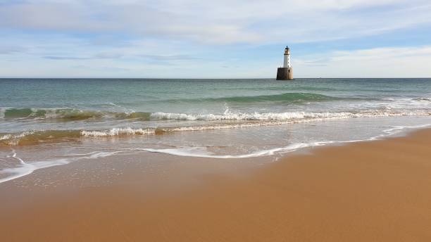 White lighthouse on platform in sea near beach