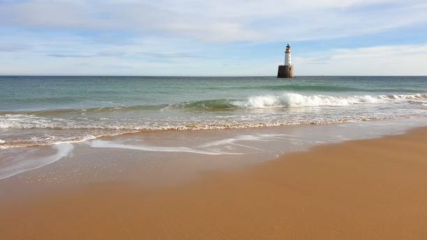 istock White lighthouse on platform in sea near beach 1130246815