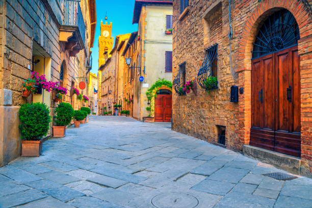 Rustic brick and stone houses decorated with colorful flowers, Italy Spectacular traditional Tuscany street view. Admirable medieval stone houses and paved street with flowery entrances, Pienza, Tuscany, Italy, Europe narrow streets stock pictures, royalty-free photos & images