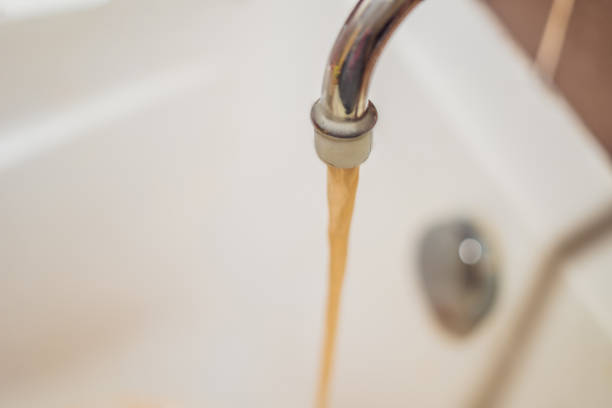 istock Dirty brown running water falling into a white sink from tap. Environmental pollution concept 1130247998