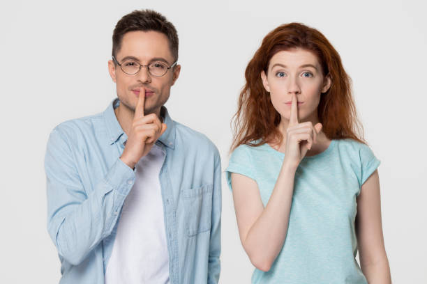 Young mute couple holding fingers on mouth keep it quiet