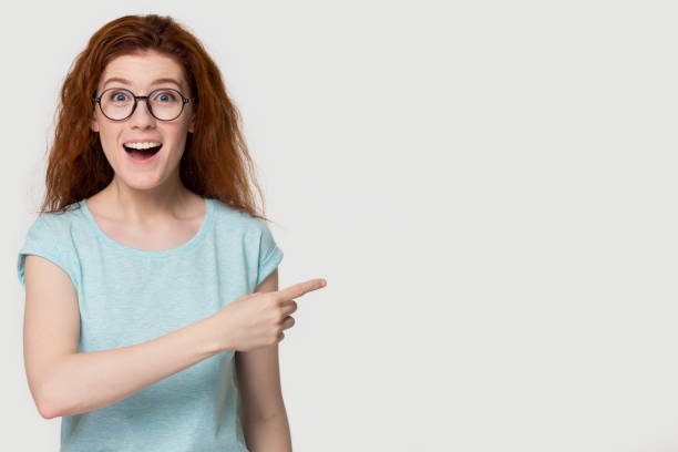 istock Funny excited red-haired girl student pointing at copy space aside 1130250093