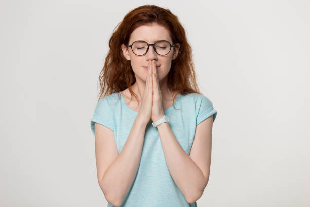 istock Happy redhead grateful woman join hands praying with hope meditating 1130250107