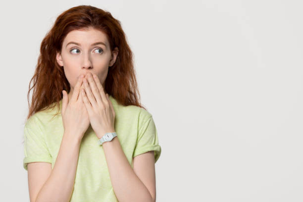 istock Shocked redhead woman cover mouth with hands looking at copyspace 1130250142