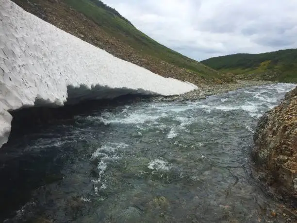 Photo of The mountain river Tahkoloch (or Klyuchevaya) flows under the glacier in the caldera of the extinct Vachkazhets volcano on the Kamchatka Peninsula, Russia.