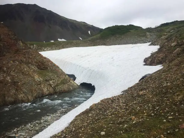 Photo of The mountain river Tahkoloch (or Klyuchevaya) flows under the glacier in the caldera of the extinct Vachkazhets volcano on the Kamchatka Peninsula, Russia.