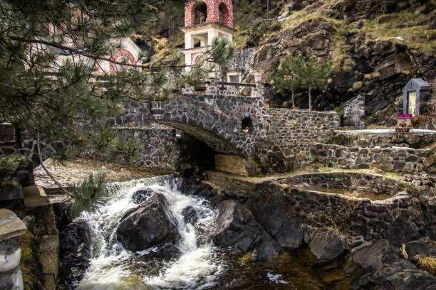 istock Small church by the river and stone bridge on fast river with small waterfall 1130254193