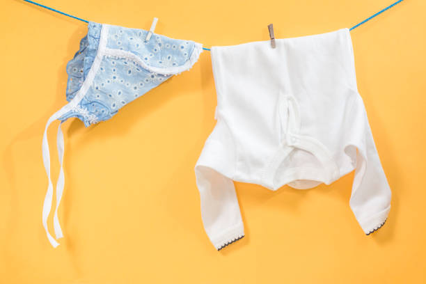 Clothesline with hanging baby clothes on yellow background