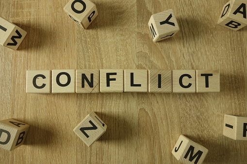 Conflict word from wooden blocks on desk