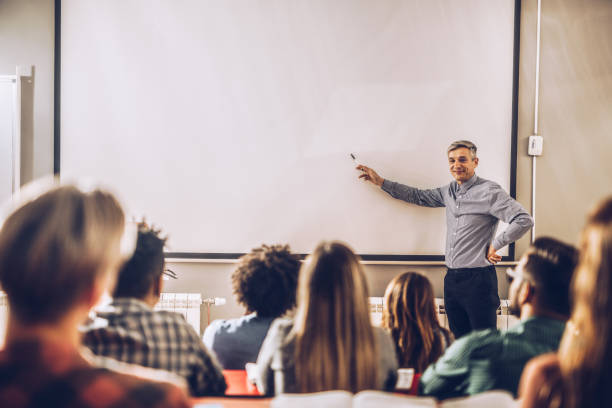 счастливый профессор преподает лекцию на визуальном экране в классе. - whiteboard education school university стоковые фото и изображения