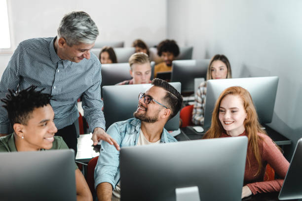 istock Happy teacher talking to student during a class at computer lab. 1130260160