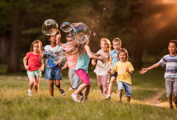 istock Carefree kids having fun with rainbow bubbles in the park. 1130264646