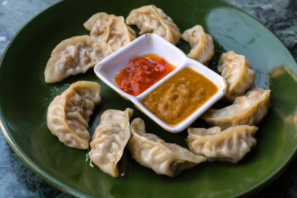 traditionelle asiatische küche. nepalesen gedämpfte knödel momo mit tomaten chutney serviert. - chinesischer kloß stock-fotos und bilder