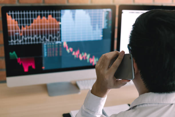 istock Agent trader man talking at telephone and checking business stock data on computer in office room. 1130269957