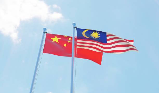 istock Malaysia and China, two flags waving against blue sky 1130272423
