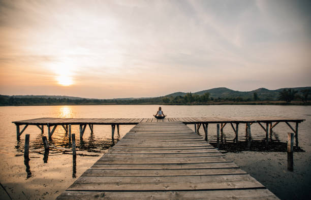 One woman, meditating by the lake outdoors alone.