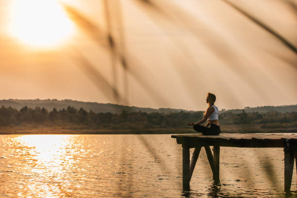 istock Lady meditating by the lake in sunset 1130278438