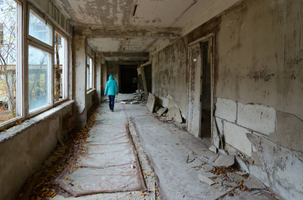турист идет по школьному коридору в заброшенном городе-призраке припять в зоне отчуждения чернобыльской аэс, украина - dead race стоковые фото и изображения