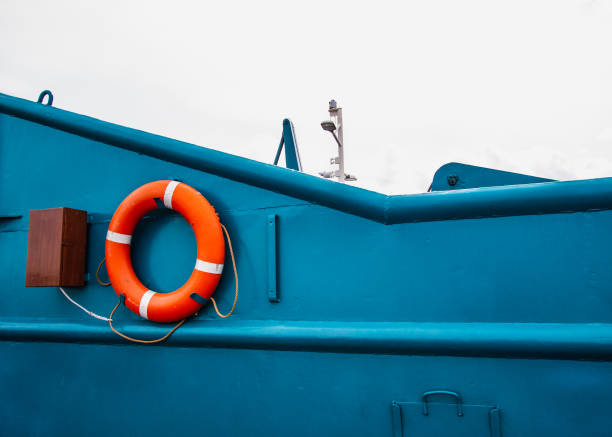 Red lifebuoy hanging on the metal surface of the blue ferry boat.