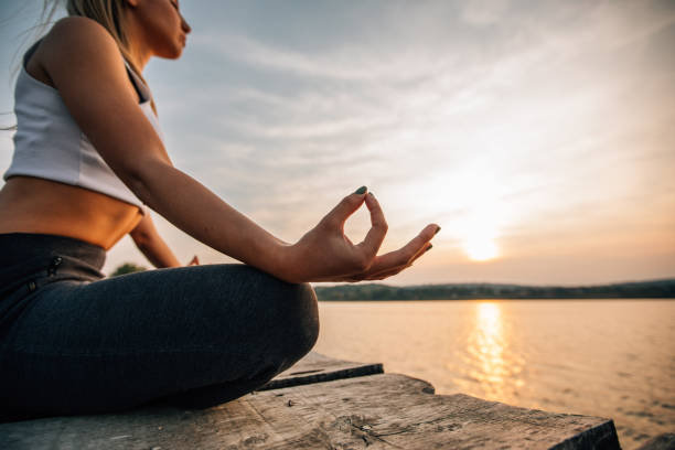 istock Meditating by the river in sunset 1130278838