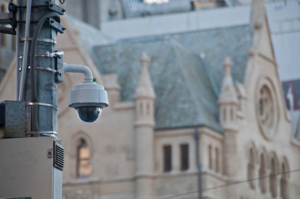 Surveillance CCTV street outdoor camera watching pedestrian near Surveillance CCTV street outdoor camera watching pedestrian near European church in city center to prevent terrorism. The photo is taken in the afternoon. cityscape videos stock pictures, royalty-free photos & images