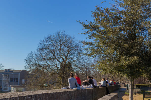 students enjoying the firs rays of sun at the city wall in maastricht - winter women zen like photography imagens e fotografias de stock